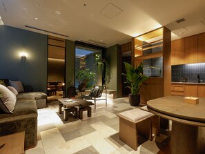 A modern living room with a sofa, coffee table, and a dining area with a round table. - Arima Hot Spring nebi (Kobe)