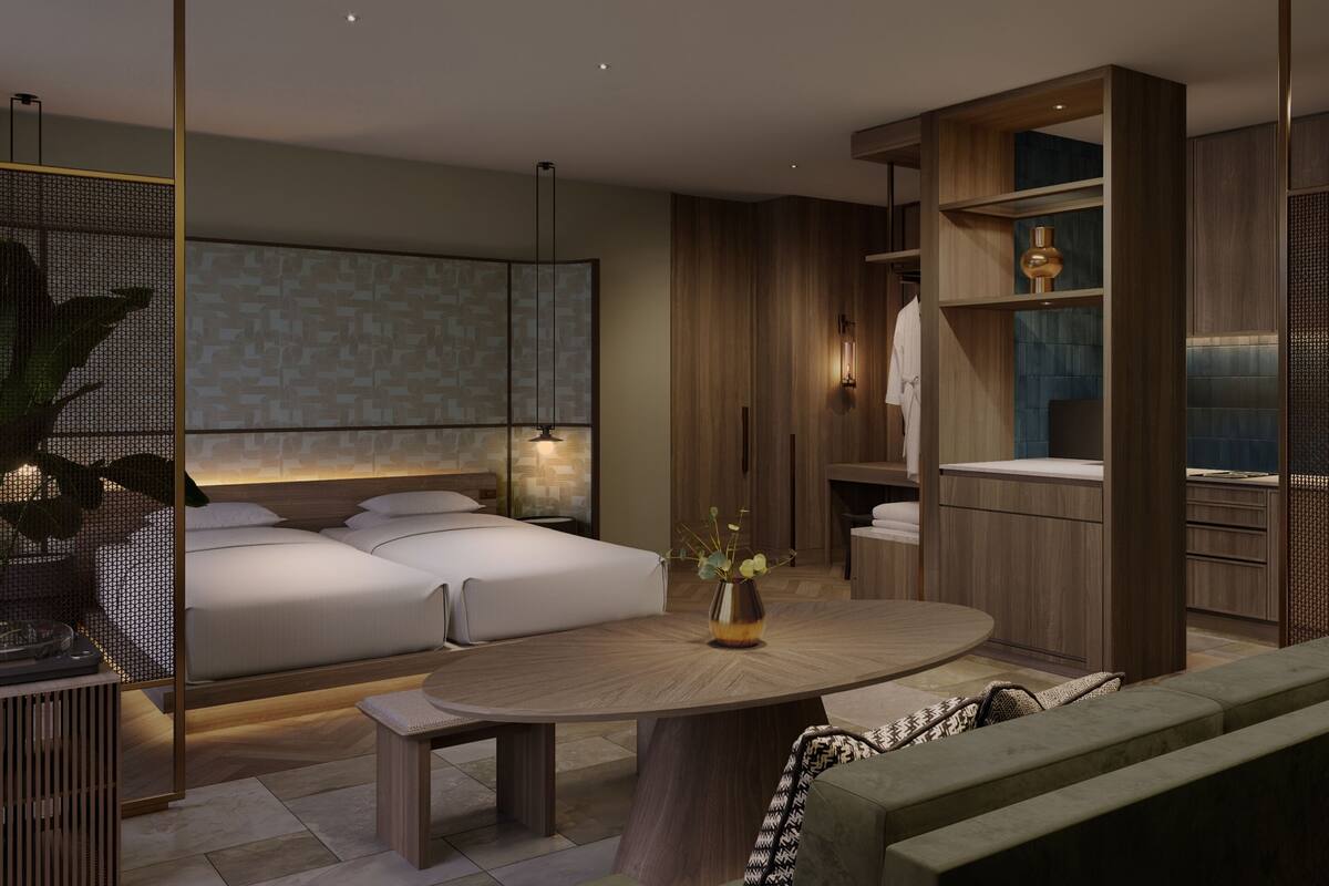 A modern bedroom with a large bed, bedside tables, a round wooden table, and built-in shelving.