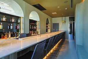 A bar area with a long counter, multiple shelves of bottles, and a seating arrangement with chairs. - Arima Hot Spring nebi (Kobe)