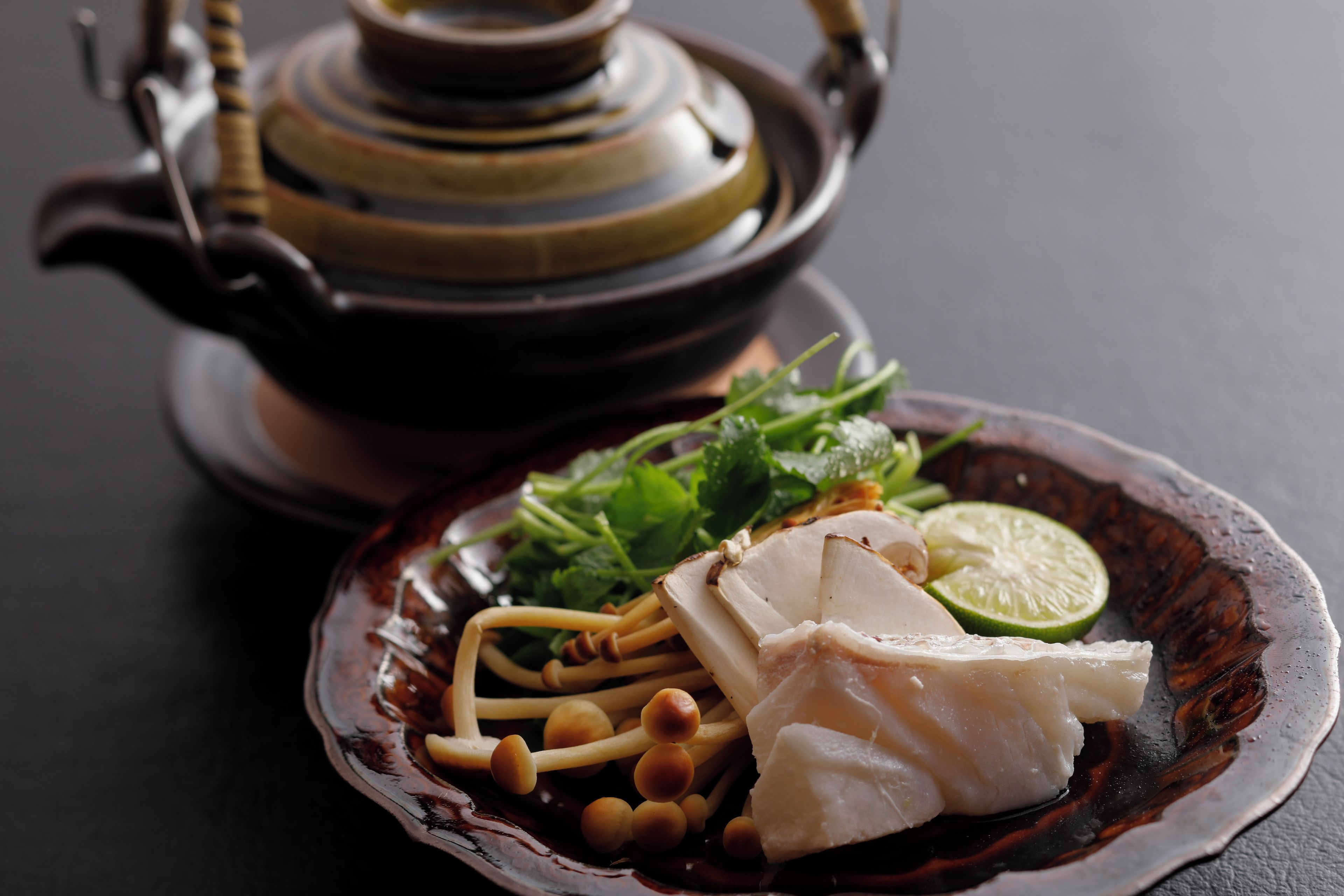 A plate of food with a teapot in the background.