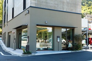 A hotel entrance with a glass facade, a visible parking area, and a clear view of the street. - Arima Hot Spring nebi (Kobe)