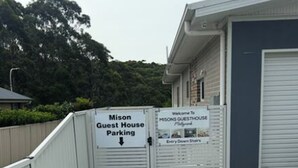 En lukket indgang til en parkeringsplads for gæster, med et skilt der angiver 'Mison Guest House Parking'.