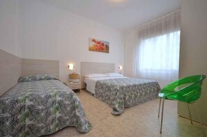Een slaapkamer met twee bedden, een groene stoel en een schilderij aan de muur.