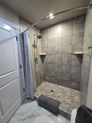 Een douche, handdoeken, zeep, toiletpapier