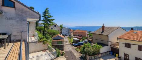 Una calle residencial con casas, cielo despejado y vista al mar.