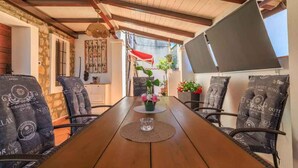 Una mesa de madera para comer con un mantel individual y una pieza decorativa de vidrio, rodeada de sillas con cojines estampados.