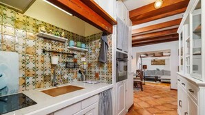Una cocina con armarios blancos, salpicadero de azulejos y techo de madera.
