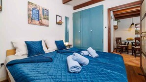 Un dormitorio con una cama grande, ropa de cama azul, un cuadro en la pared y un armario azul.