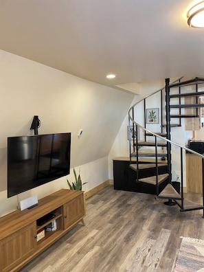 Ein modernes Wohnzimmer mit Flachbildfernseher, einer Holzeinrichtungsanlage und einer Wendeltreppe.