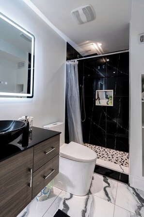 A modern bathroom with a black marble shower, a white toilet, and a dark wooden vanity with a mirror. - Luxury 2BR/2BA Modern B Apartment in Ajax, Toronto (Ajax)
