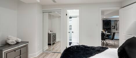 Een slaapkamer met een bed, een kast, een spiegel en uitzicht op de keuken.
