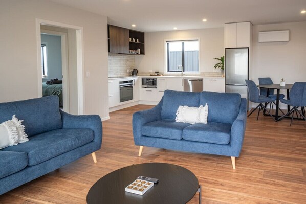 Un salon moderne avec deux canapés bleus, une table basse et un coin repas comprenant une table et des chaises.