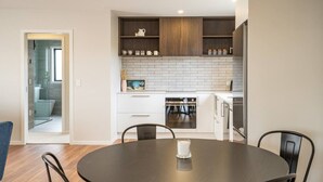 A modern kitchen with white cabinets, a brick backsplash, and wooden shelves. - NEW two bedroom home in Te Anau (Te Anau)