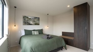 A bedroom with a bed, a painting, a wardrobe, and a window. - NEW two bedroom home in Te Anau (Te Anau)