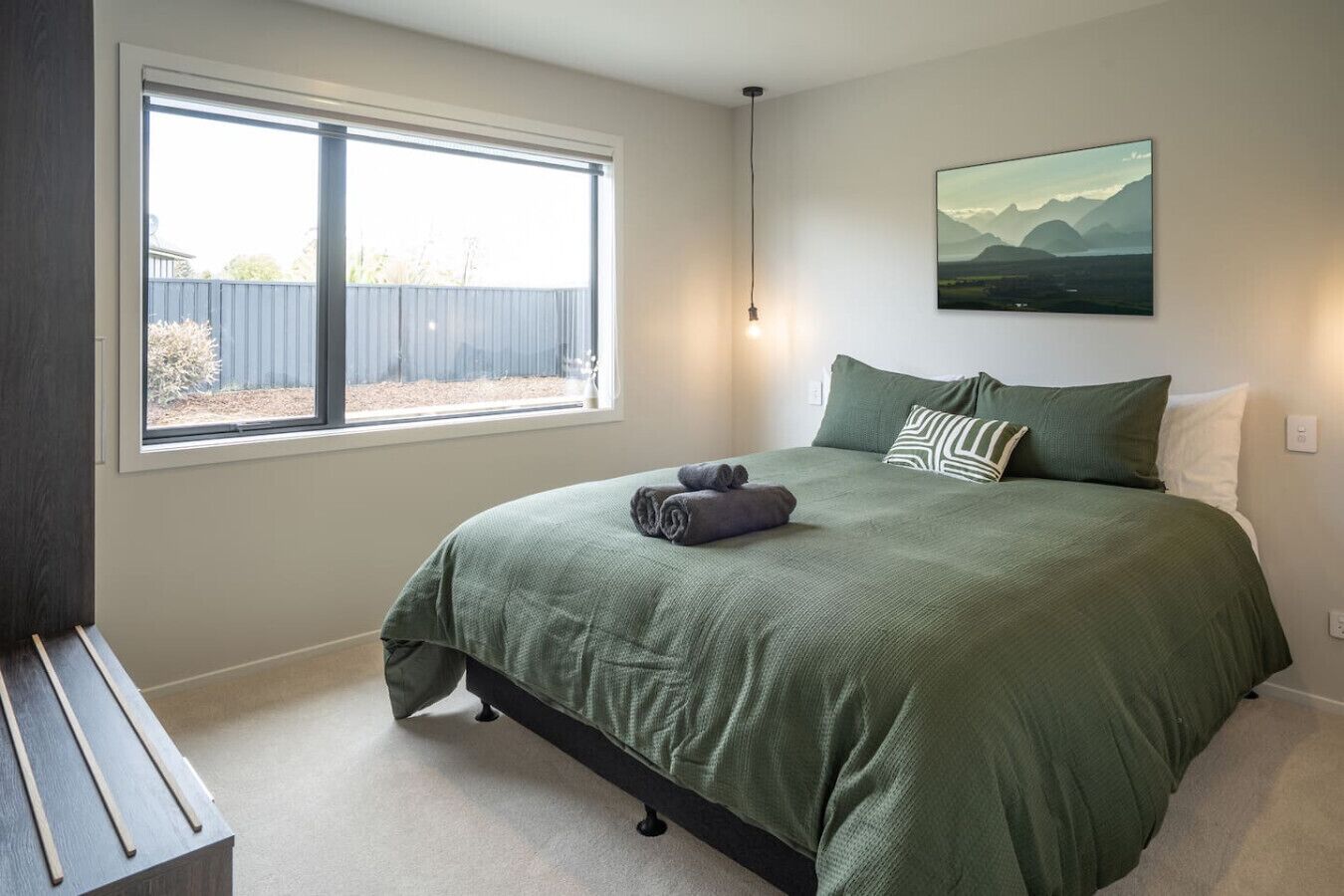 Quarto com cama grande, janela e pintura na parede.