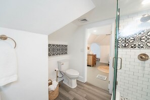 Ein Badezimmer mit Toilette, einer Duschkabine aus Glas und einer auffälligen Rückwand.