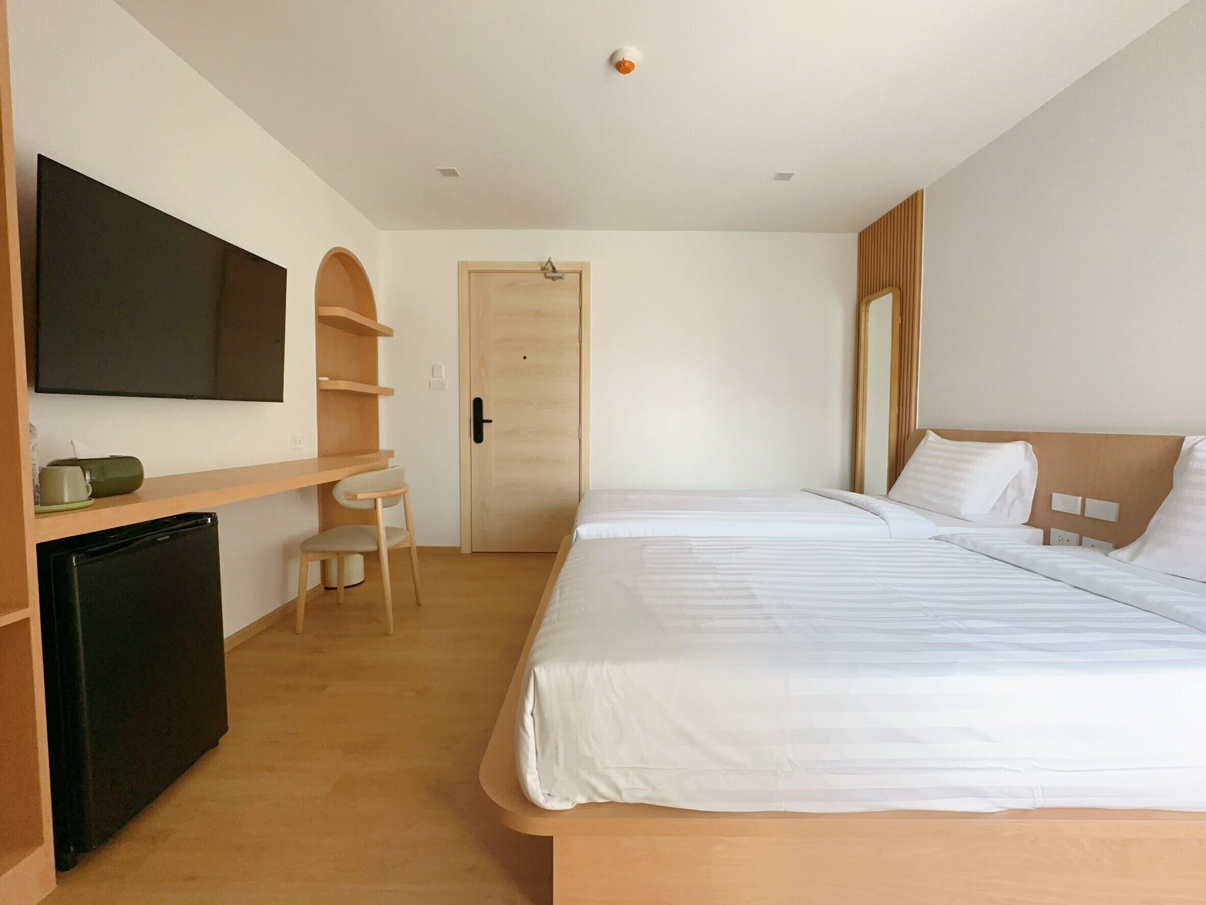 A hotel room with a bed, a desk, a chair, a television, and a door.