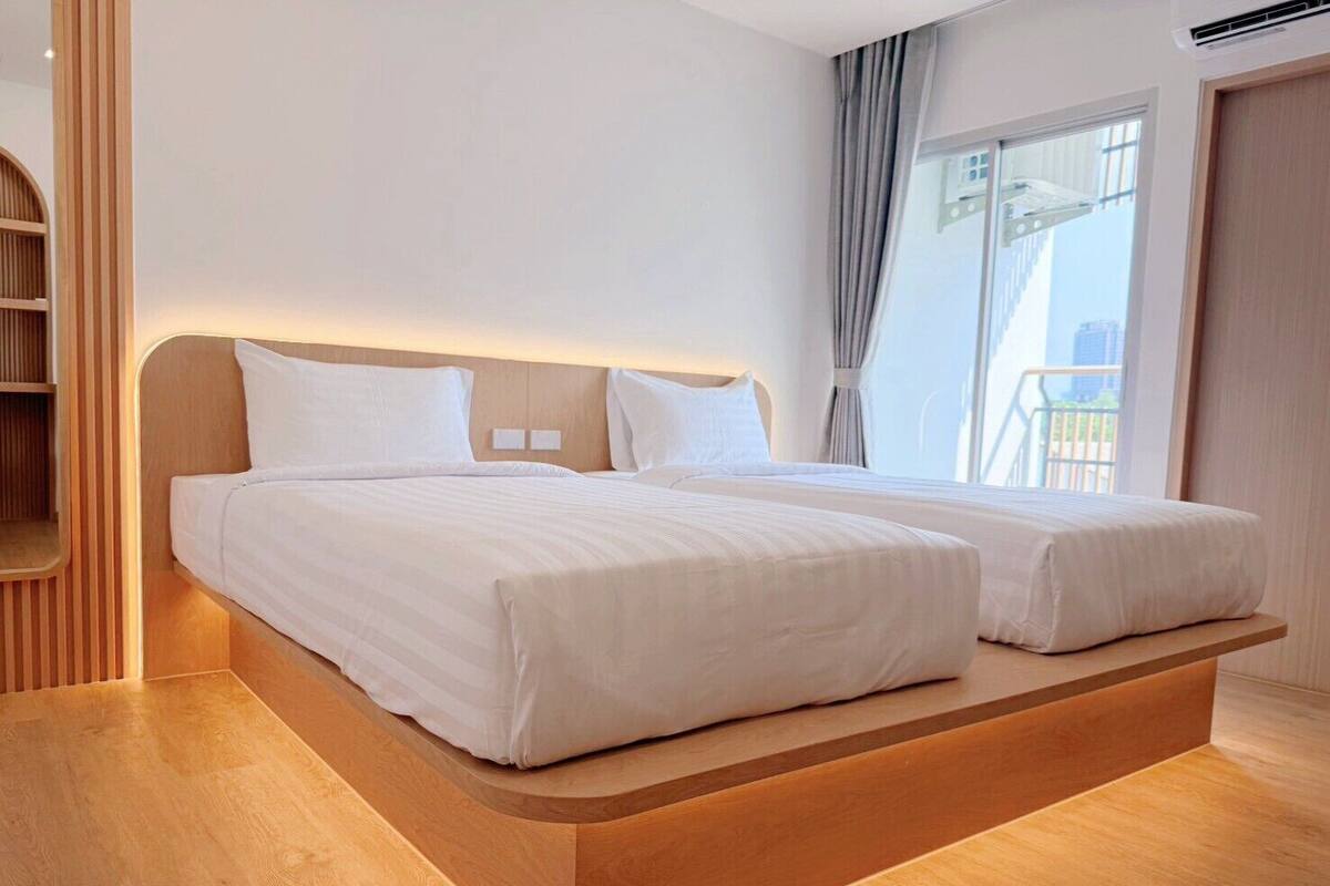 Quarto de hotel moderno com uma cama plataforma de madeira, uma janela ampla com vista e um guarda-roupa embutido.