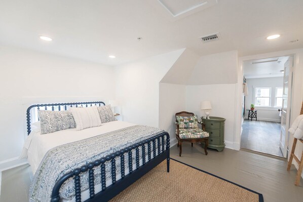 A bedroom with a bed, a chair, a nightstand, and a view of a hallway. - The Palmetto Room with Private Ensuite in Boutique B&B, The Parrish Grove Inn (Cocoa)