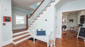 A staircase with white railings and wooden steps leading to a landing area with a bench and a small stool.