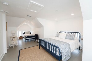 A spacious bedroom with a large bed, a smaller bed in the background, a bedside table with a lamp, and a ceiling light. - The Palmetto Room with Private Ensuite in Boutique B&B, The Parrish Grove Inn (Cocoa)