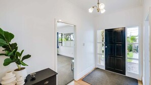 A clean, modern hallway with a black door, a potted plant, and a small table with decorative items. - Charming on Cambridge (Napier)