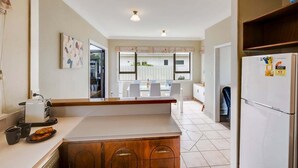 A modern kitchen with a central island, white cabinetry, and a refrigerator. - Charming on Cambridge (Napier)
