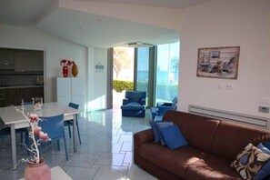 A modern living room with a brown sofa, blue chairs, a dining table, and a kitchen in the background. - Villa Fortunata, Terracina, Italy (Terracina)