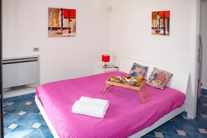 Una habitació amb un llit, una taula de nit amb una làmpada i obres d'art a les parets.
