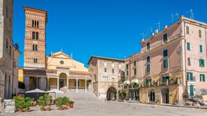 A historic square with a prominent tower, a church with a dome, and traditional buildings with balconies and windows.