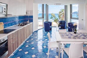 A modern kitchen with a blue and white tile backsplash, a built-in oven, and a large window overlooking the sea.