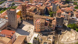 An aerial view of a historic town with a prominent square, ancient ruins, and a large theater.
