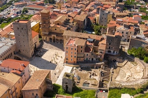 An aerial view of a historic town with a prominent square, ancient ruins, and a large theater.