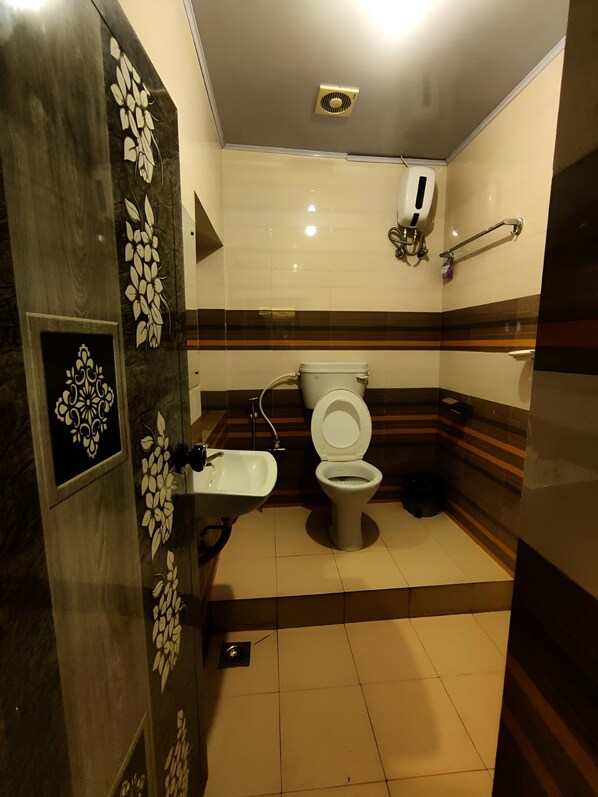 A bathroom with a toilet, sink, and handrail.
