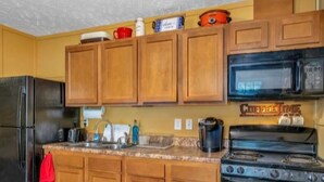 Una cocina con armarios de madera, un refrigerador de acero inoxidable, un microondas, una estufa y varios electrodomésticos.