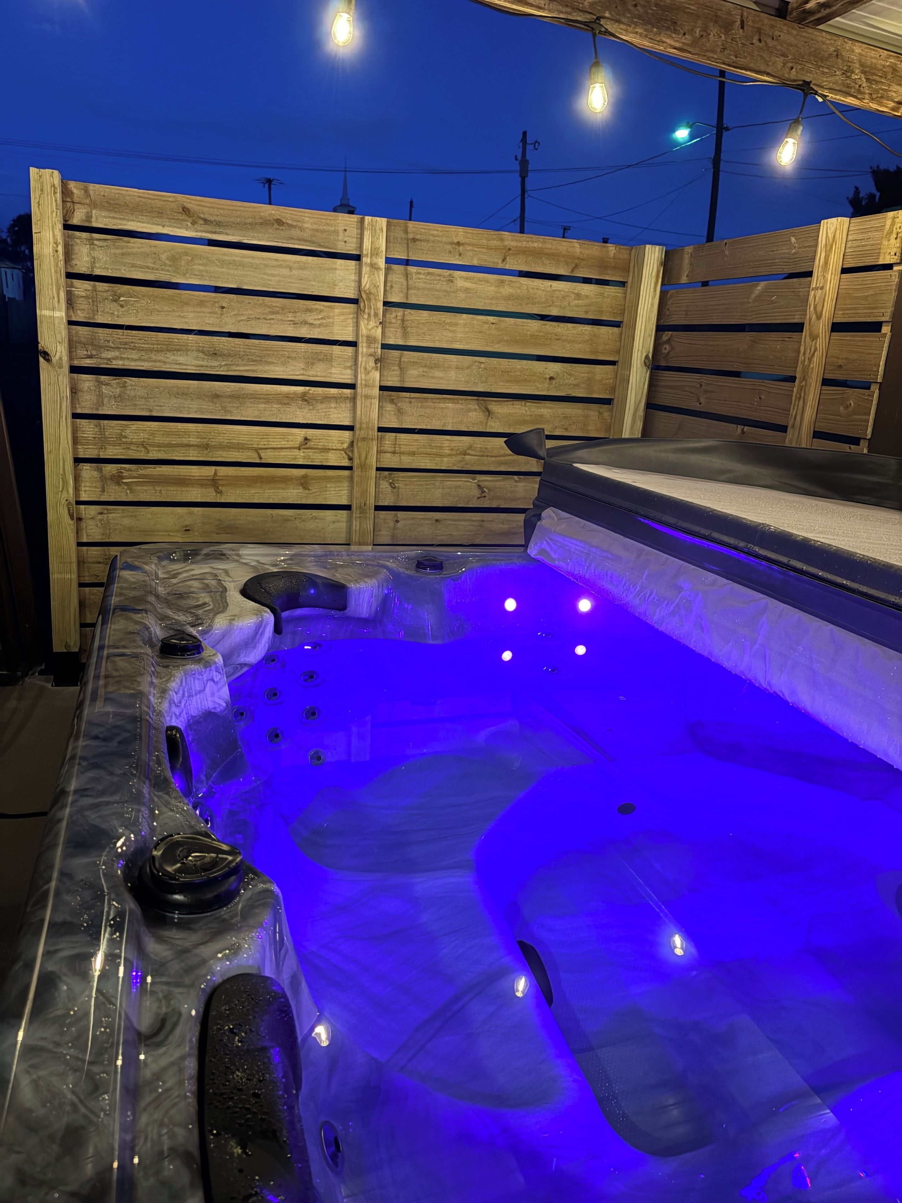 Een hottub met een houten omheining op de achtergrond.