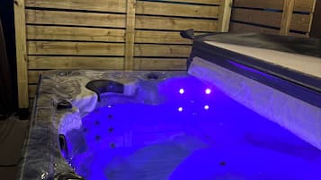 Een hottub met een houten omheining op de achtergrond.