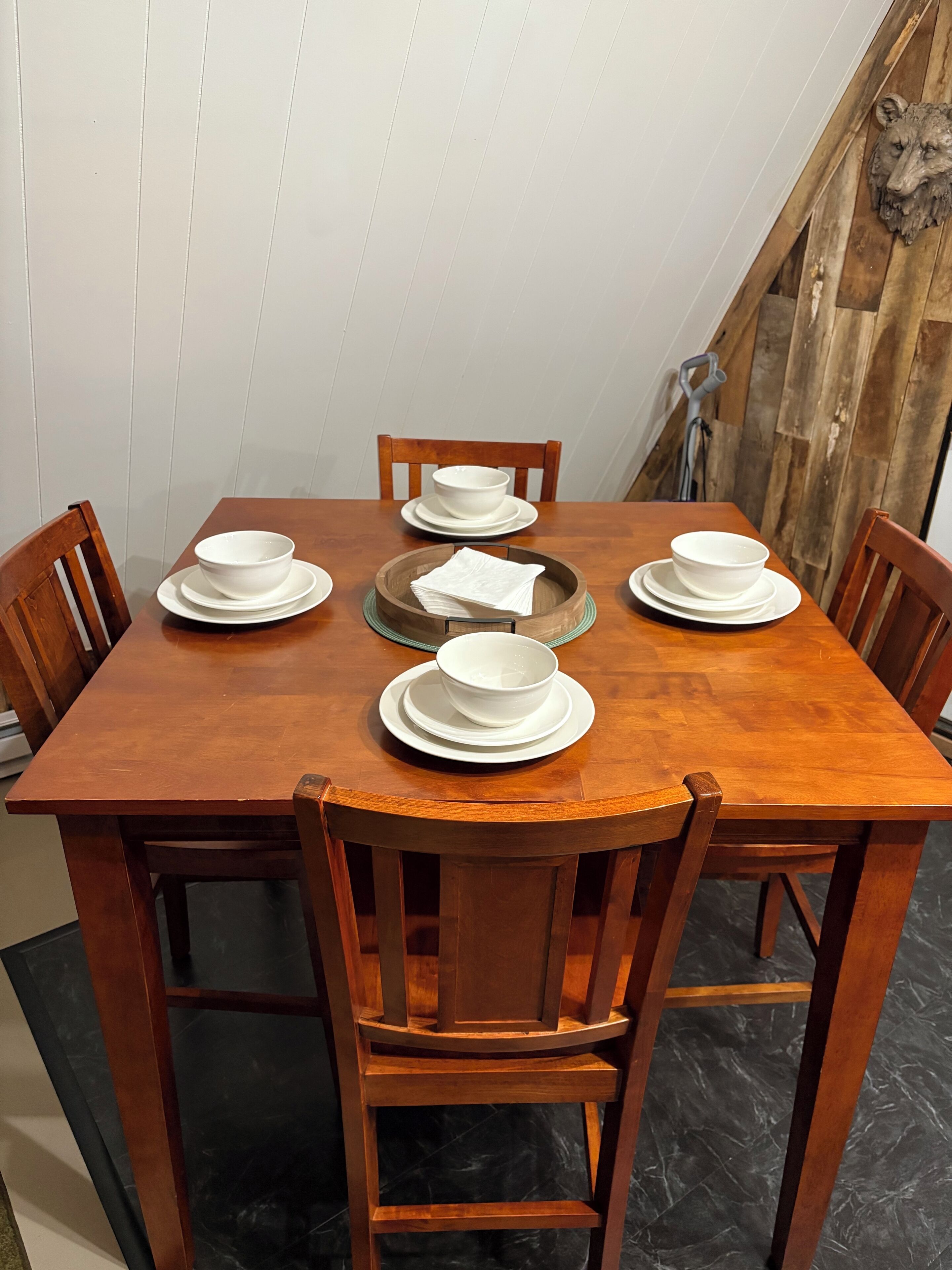 Une table à manger en bois, sur laquelle sont disposées des assiettes et des bols blancs, entourée de chaises en bois.