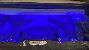 Een hottub met een houten terras en een houten hek op de achtergrond.