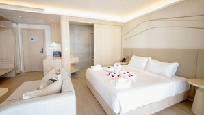 Una habitación de hotel moderna con una cama grande, una zona de estar, una ducha y un escritorio pequeño.
