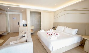 Une chambre d’hôtel moderne dotée d’un grand lit, d’un coin salon, d’une douche et d’un petit bureau.