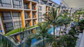 Un hotel de varios pisos con balcones, piscina y palmeras.
