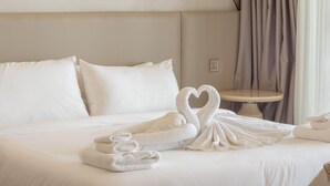 Habitación de hotel con una cama bien hecha, una mesita redonda y una decoración de toallas con forma de cisne.