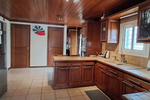 Eine Küche mit Holzausstattung, einer großen Kochinsel und Fliesenboden.