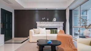 En moderne stue med en hvid sofa, et sort sofabord og en pejs med dekorative genstande.