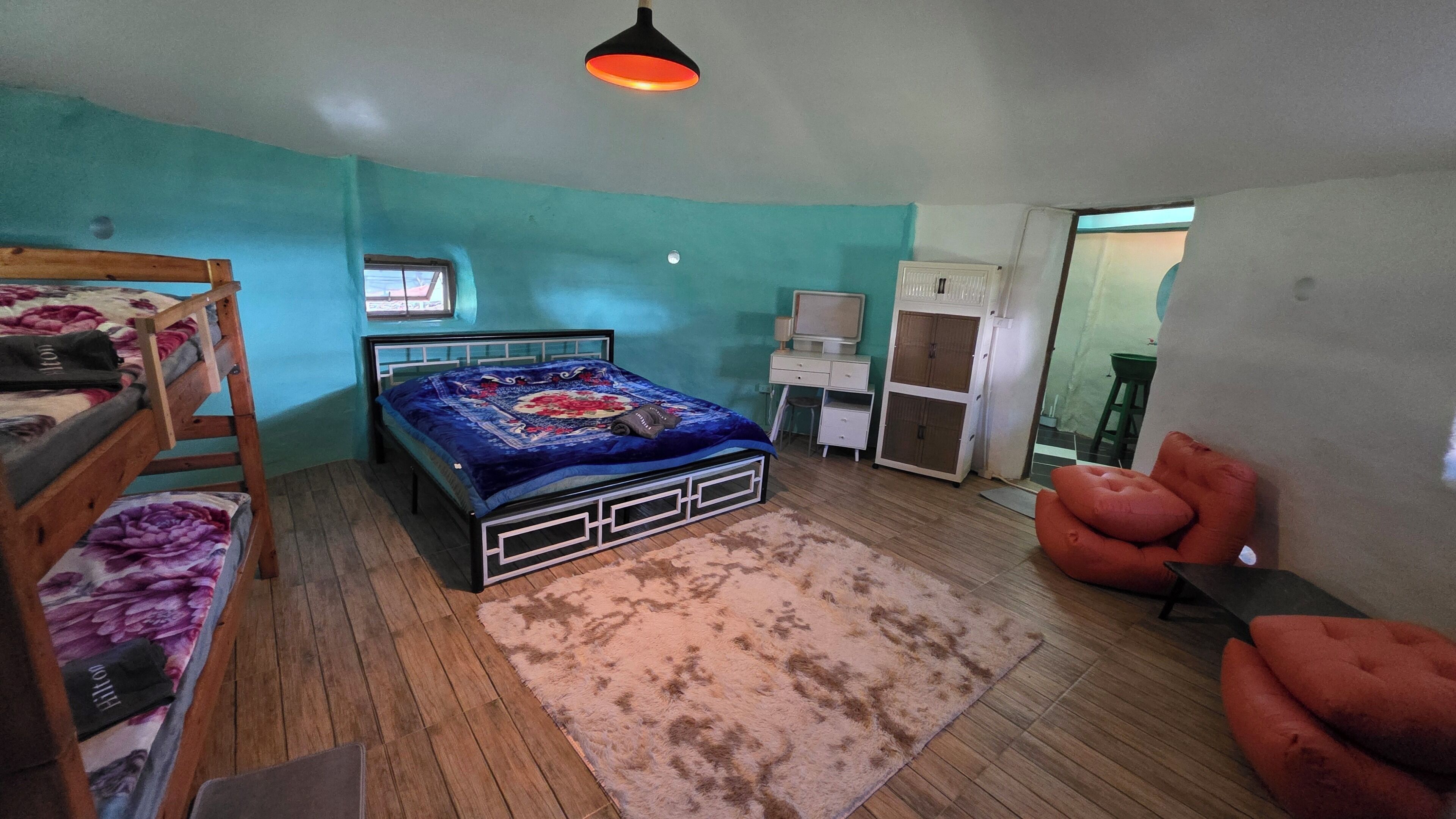 Een slaapkamer met een bed, bureau, stoel en een kledingkast.