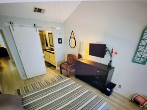 A room with a bed, a dresser, a chair, a TV, and a window. - In the trendy, funky & walkable South Congress area — 2-bedroom condo in Austin! (Austin)