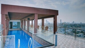 A rooftop pool with a glass barrier, seating area, and a city view. - Quan Cuong Hotel (Da Nang)