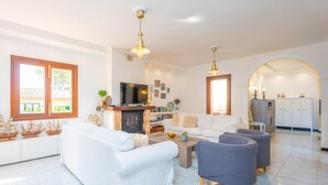 A modern living room with a fireplace, white sofas, a coffee table, and a TV. - HORABAIXA - Summer house with private pool and WiFi in Portopetro (Santanyí)