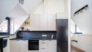 A modern kitchen with white cabinets, a black countertop, and a stainless steel refrigerator.